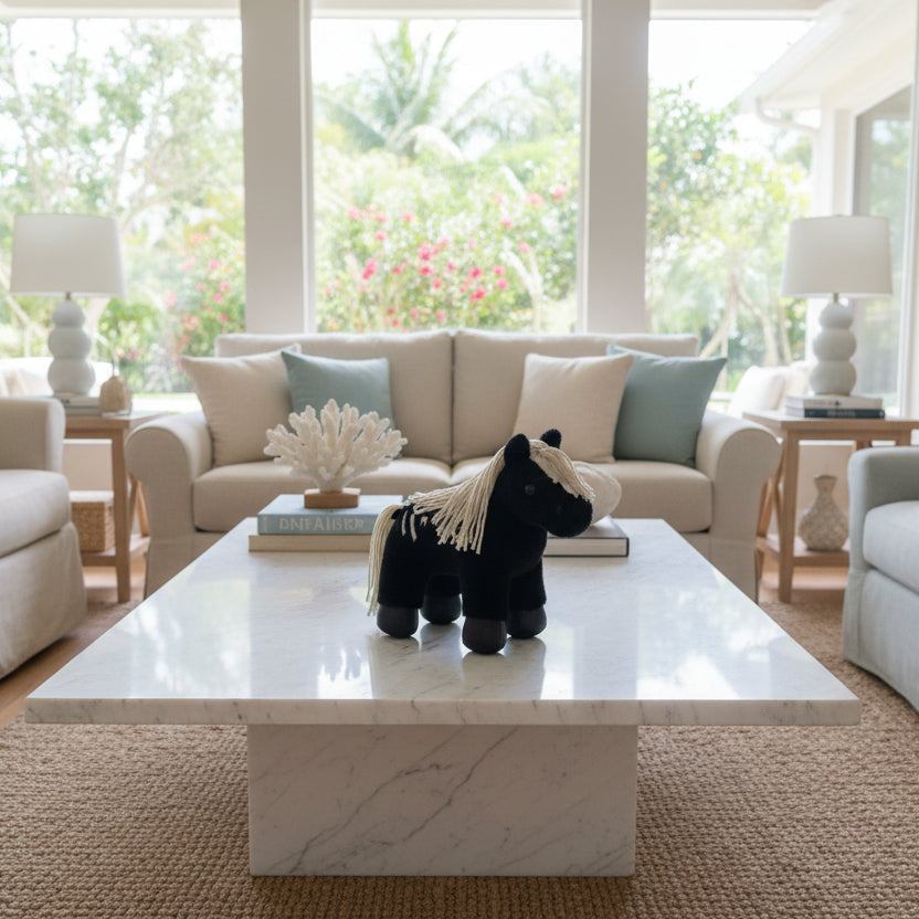A small black plush toy horse with a cream-colored yarn mane and tail.