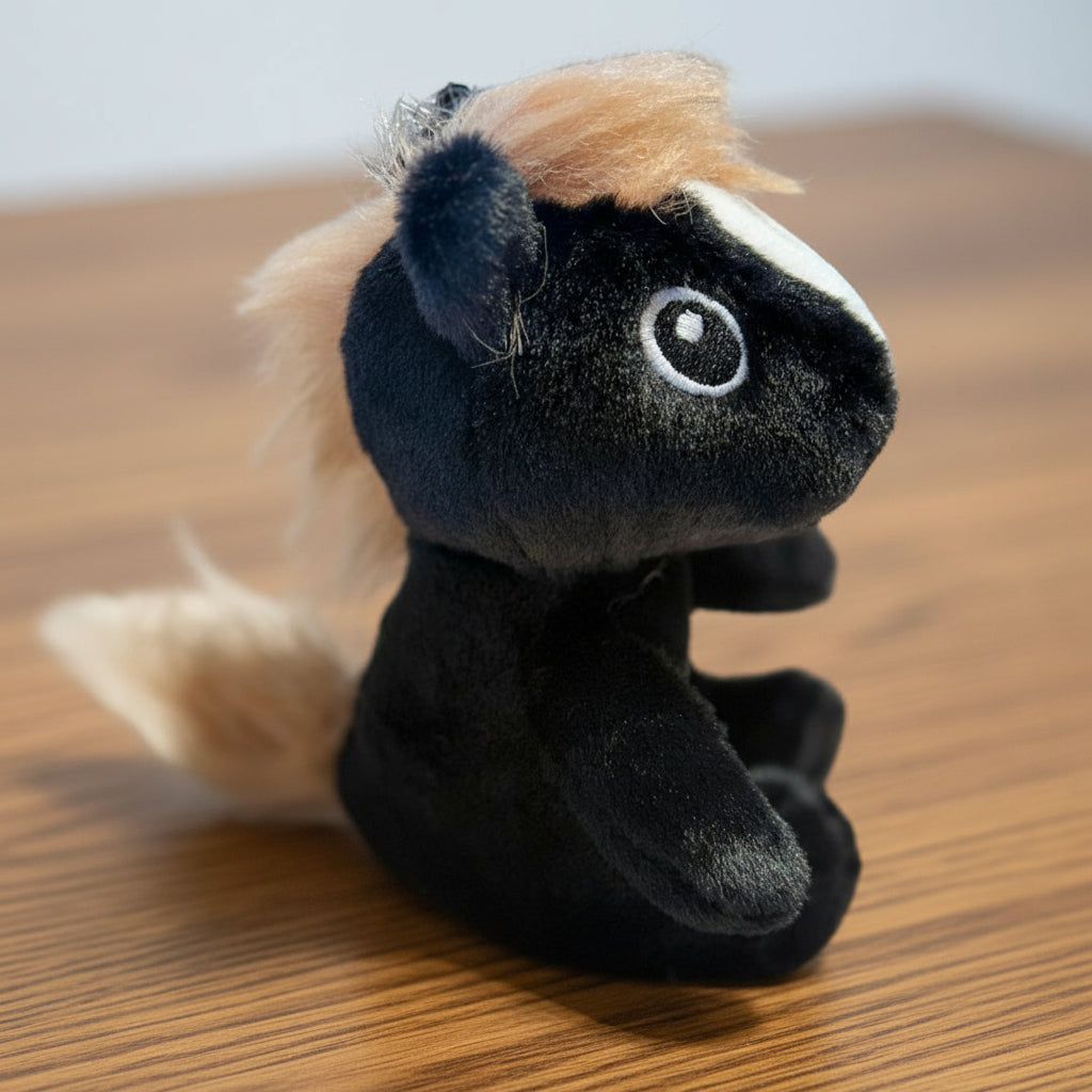 Plush toy horse with black body and beige mane on a wooden table